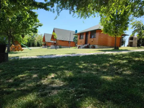 Pogled na drvene kuće u uređenom dvorištu sa travnjakom i drvećem. - image 12