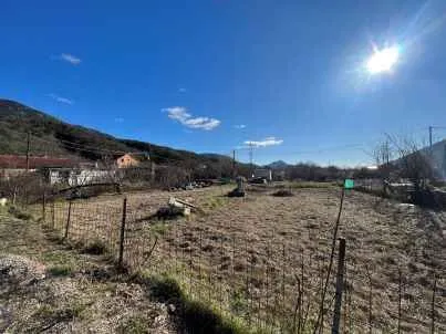 Pogled na ograđeni plac sa brdima u pozadini. - image 2
