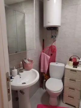 Smaller bathroom with a washbasin, toilet, shower cabin, and water heater. - image 6