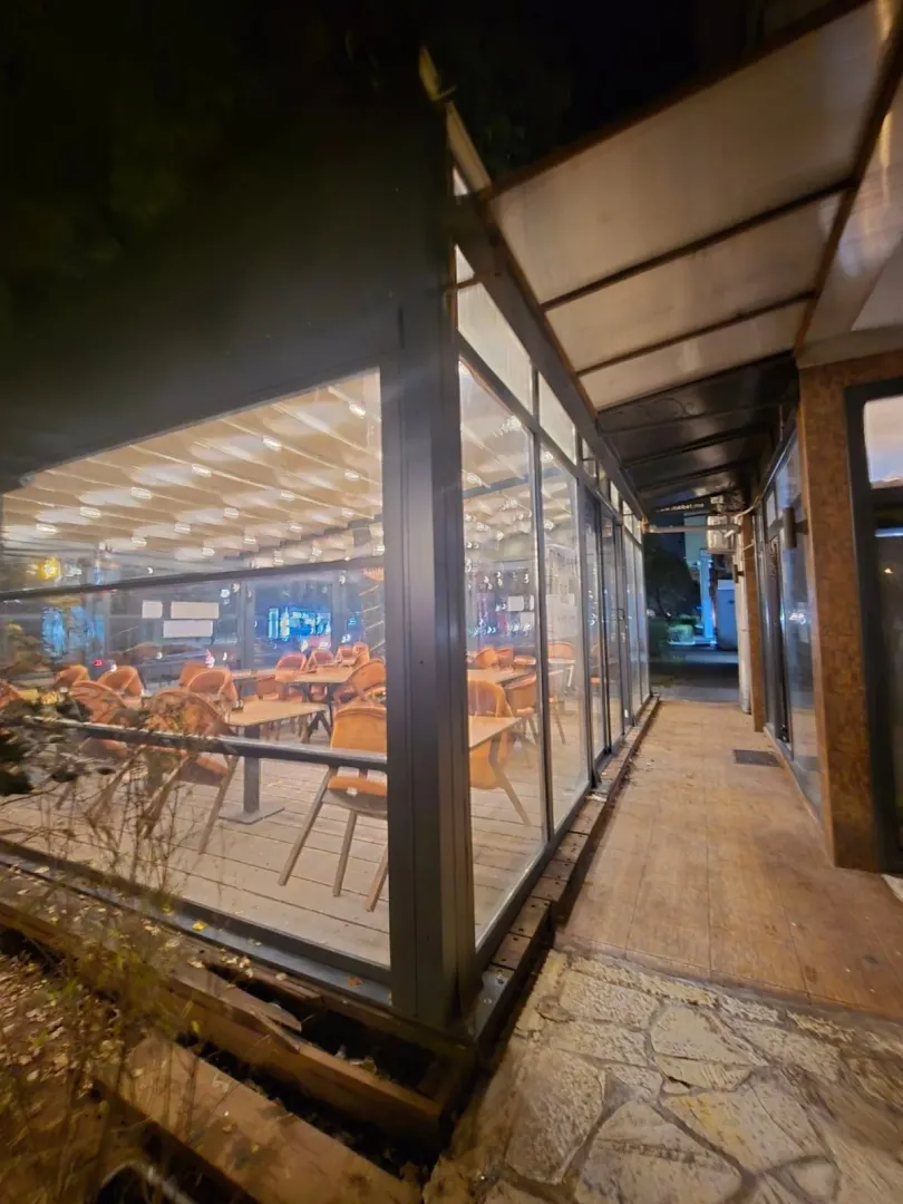 View of the exterior of the commercial space with a glass storefront and terrace at night.