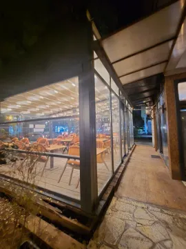 View of the exterior of the commercial space with a glass storefront and terrace at night. - image 2