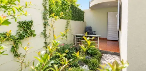Small landscaped courtyard with greenery and a pathway in front of the entrance. - image 6