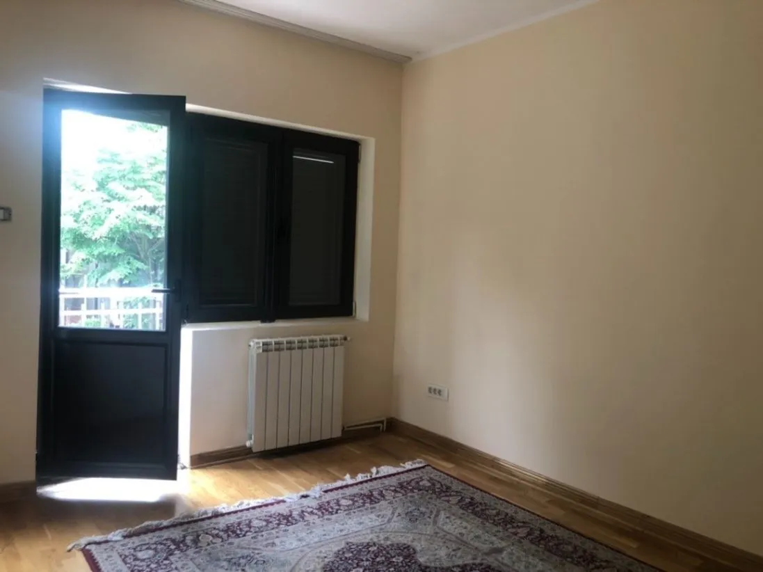 An empty room with parquet flooring, a radiator, and a balcony door.