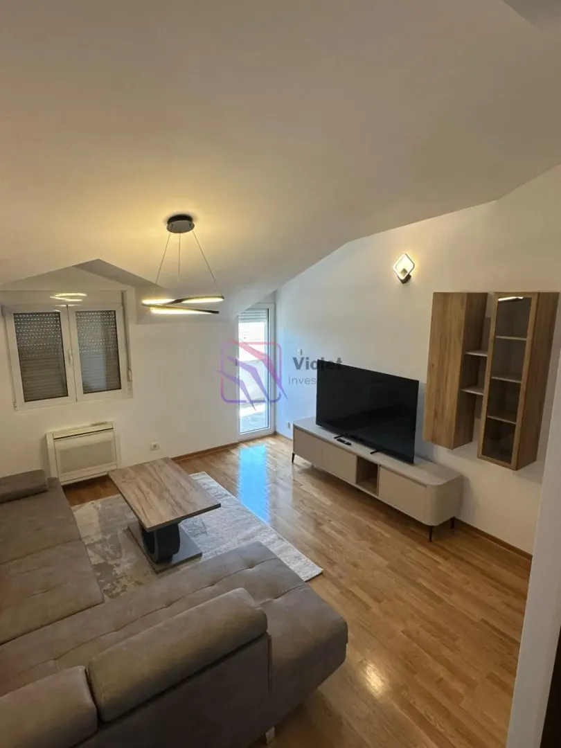 Living room with a sofa, TV, and wooden flooring.