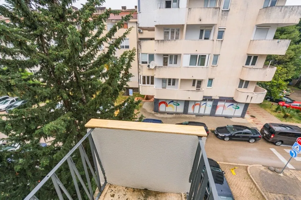 View from the balcony overlooking surrounding buildings, parking lot, and trees.