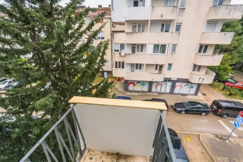 View from the balcony overlooking surrounding buildings, parking lot, and trees. - image 6
