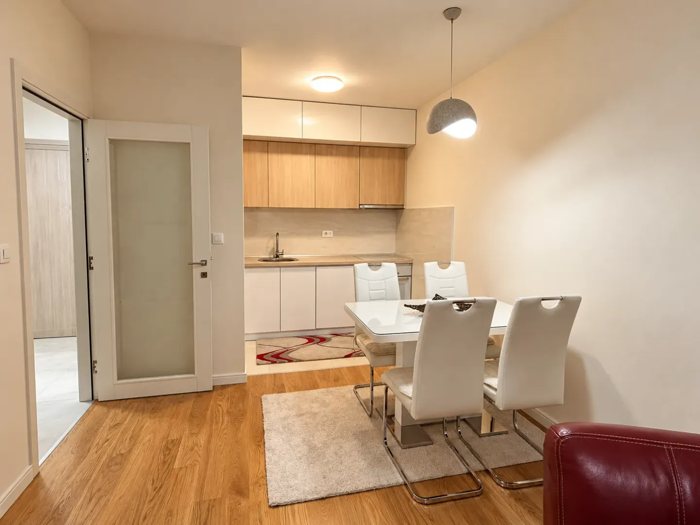 Kitchen with dining area equipped with white and wooden units.