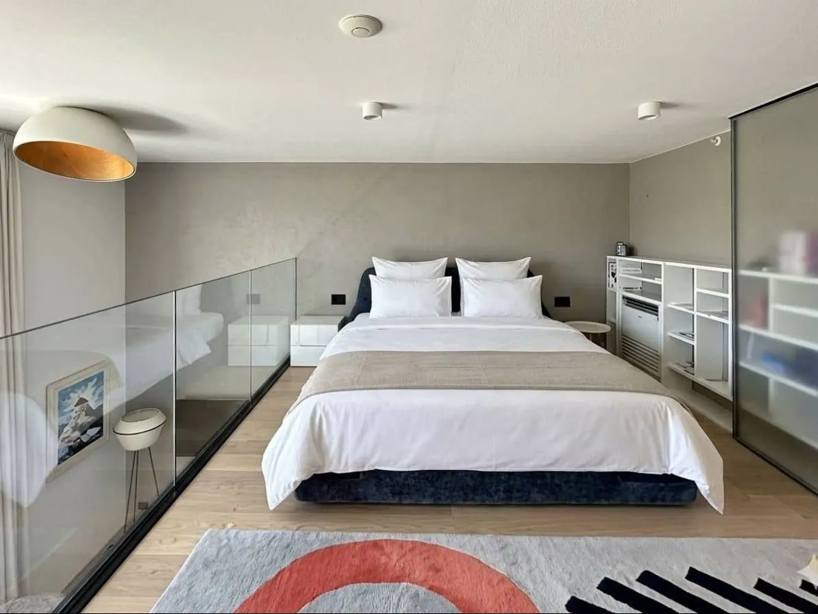 Modern bedroom with a double bed and a glass partition on the gallery.
