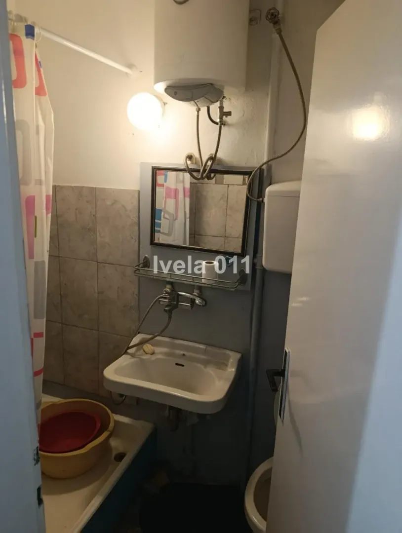 Manje kupatilo sa umivaonikom, ogledalom i tuš kabinom.