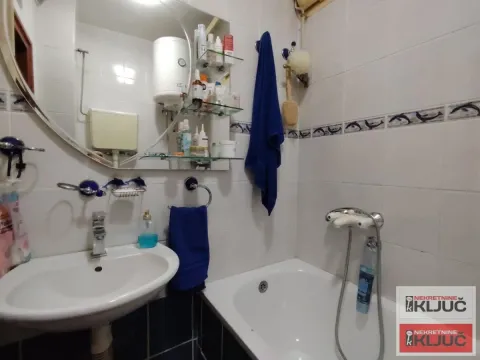 Manje kupatilo sa umivaonikom, ogledalom i kadom obloženom pločicama. - image 9