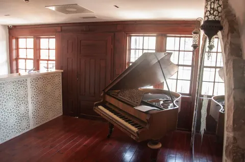 Living room with wooden flooring, a piano, and large windows. - image 11