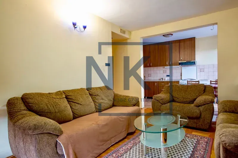 Living room with a sofa set and a view of the kitchen in the background.