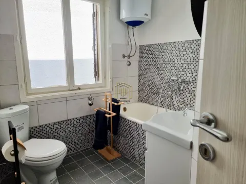 Bathroom equipped with a bathtub, washbasin, toilet, and a window. - image 3