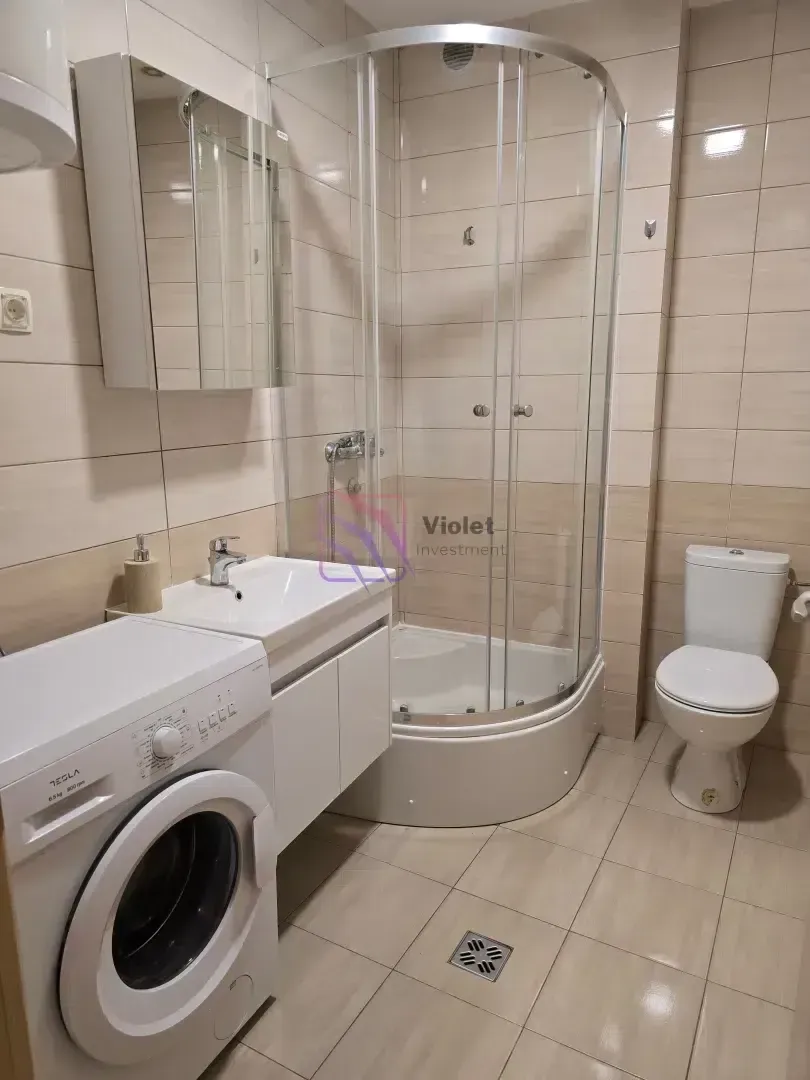 Bathroom equipped with a shower cabin, washbasin, toilet, and washing machine.