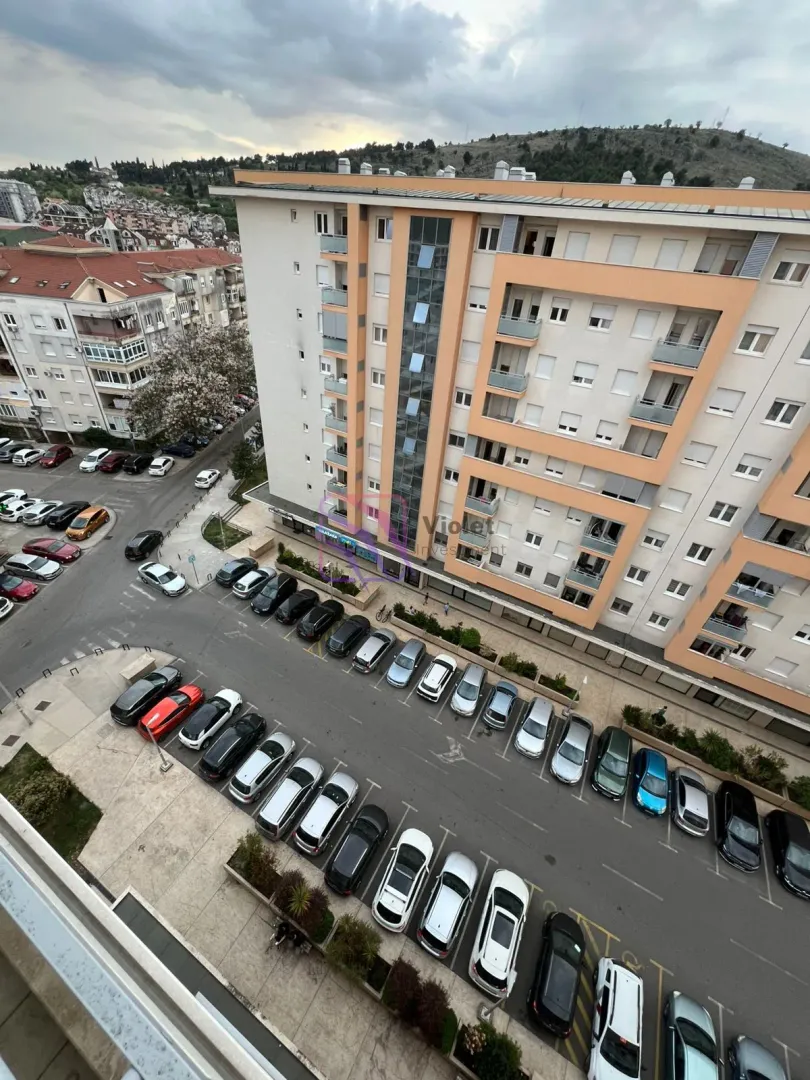 Pogled iz visine na gradsko naselje i parking ispred zgrade.