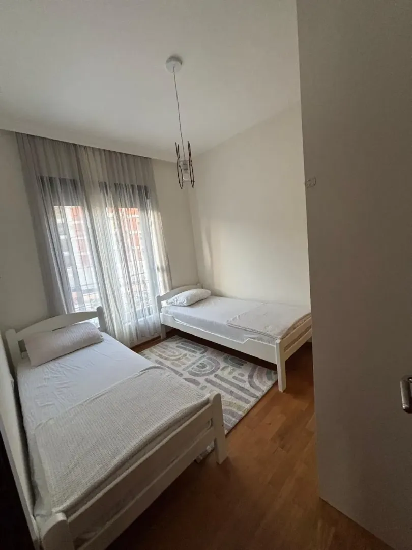 Bedroom with two single beds and a window with curtains.