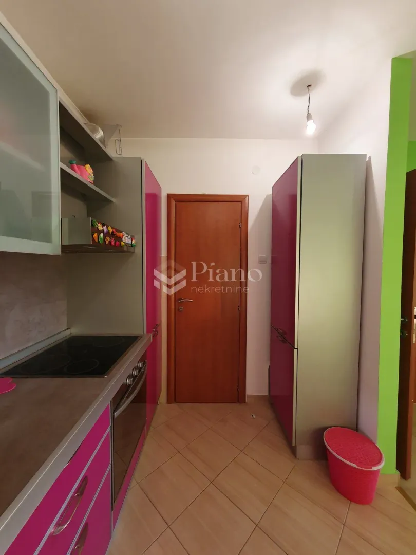 Smaller kitchen with pink elements and built-in appliances.