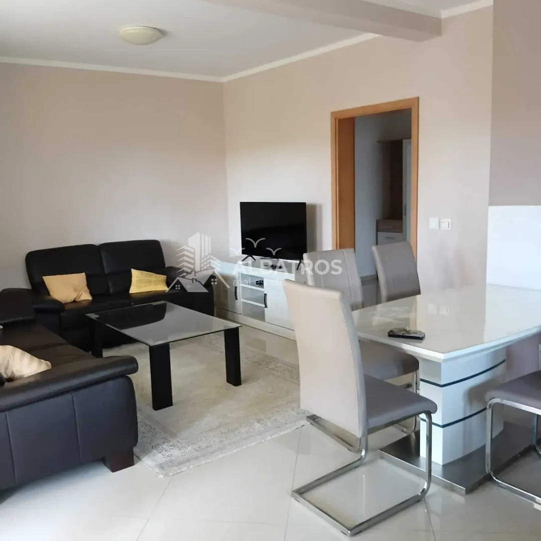 Living room with a sofa set, television, and dining table.