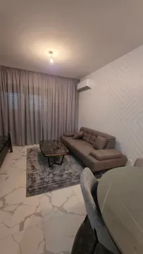 Living room with a sofa, coffee table, and dining table. - image 2