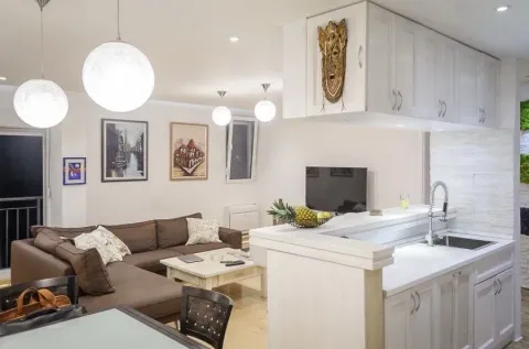 Living room with a sofa and dining area connected to the kitchen. - image 2