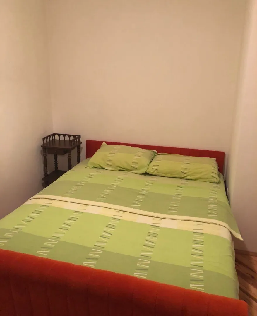 Spavaća soba sa bračnim krevetom i noćnim stočićem.