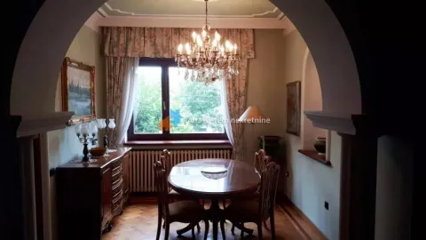 Dining room with a wooden table and chairs, a large chandelier, and a window. - image 13