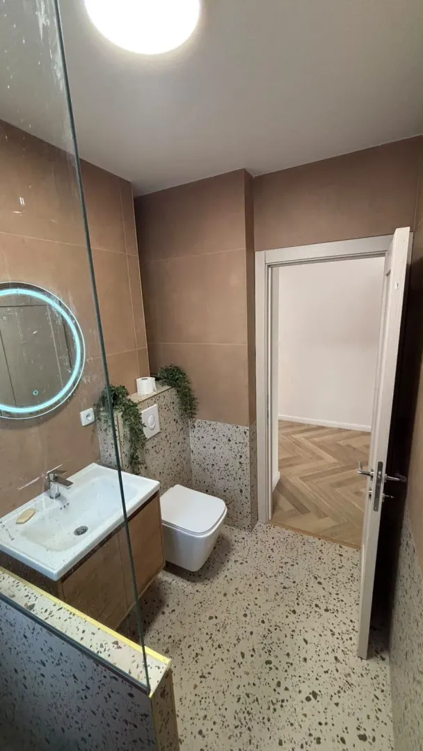 Modernly equipped bathroom with a washbasin, toilet, and a glass shower partition.