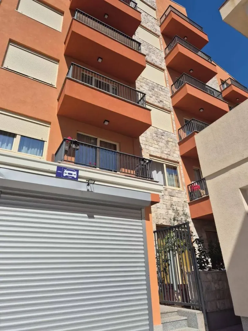 Exterior of a multi-family residential building with balconies and a garage entrance.