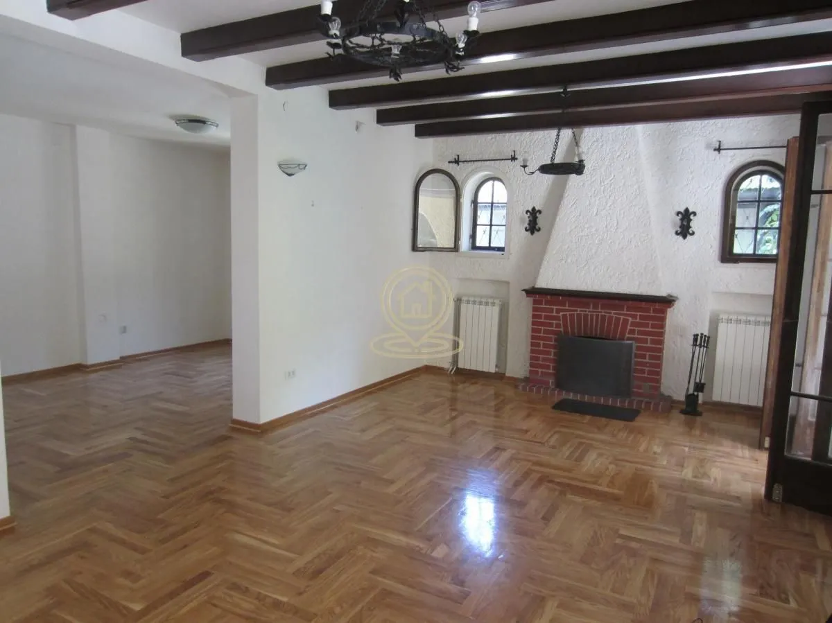 Living room with a fireplace and exposed wooden ceiling beams.