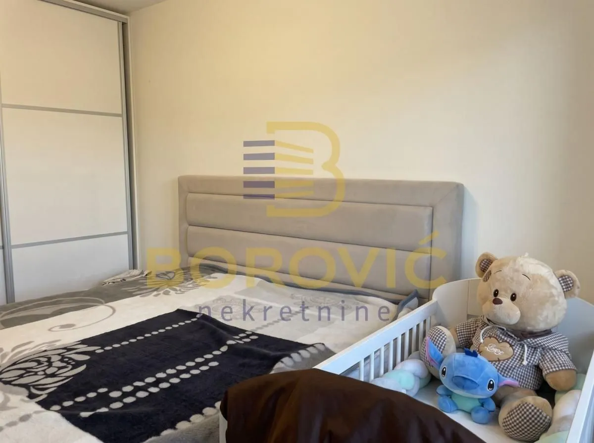 Spavaća soba sa bračnim krevetom i krevetcem za bebe.