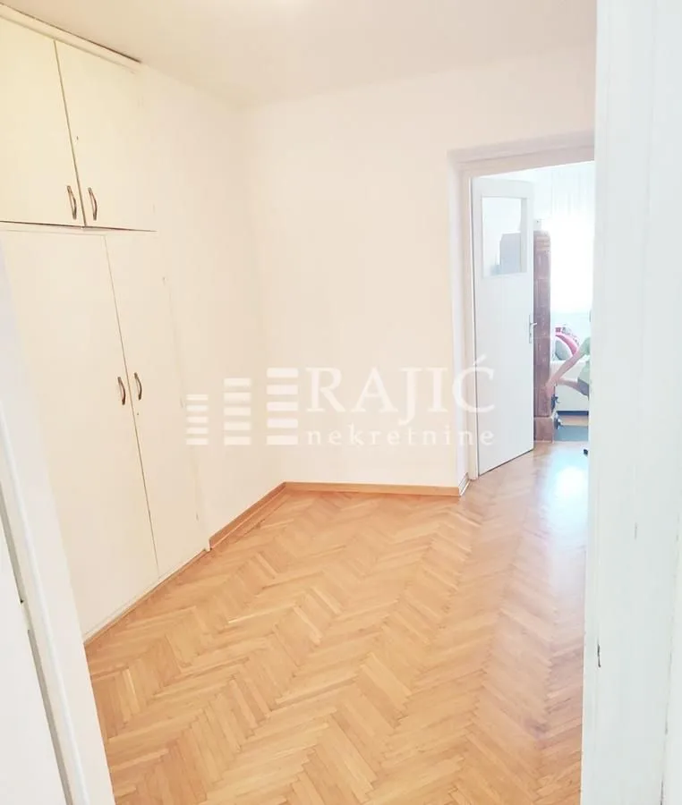 Empty room with a built-in wardrobe and parquet flooring.