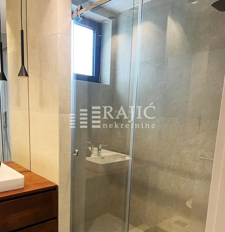 Modern bathroom with a walk-in shower and washbasin.