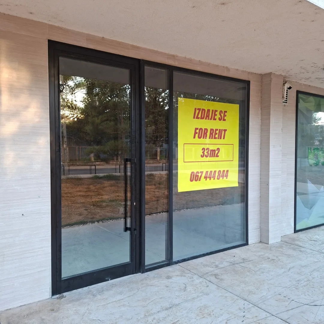 Facade of a commercial space with a glass shop window and a for rent sign.