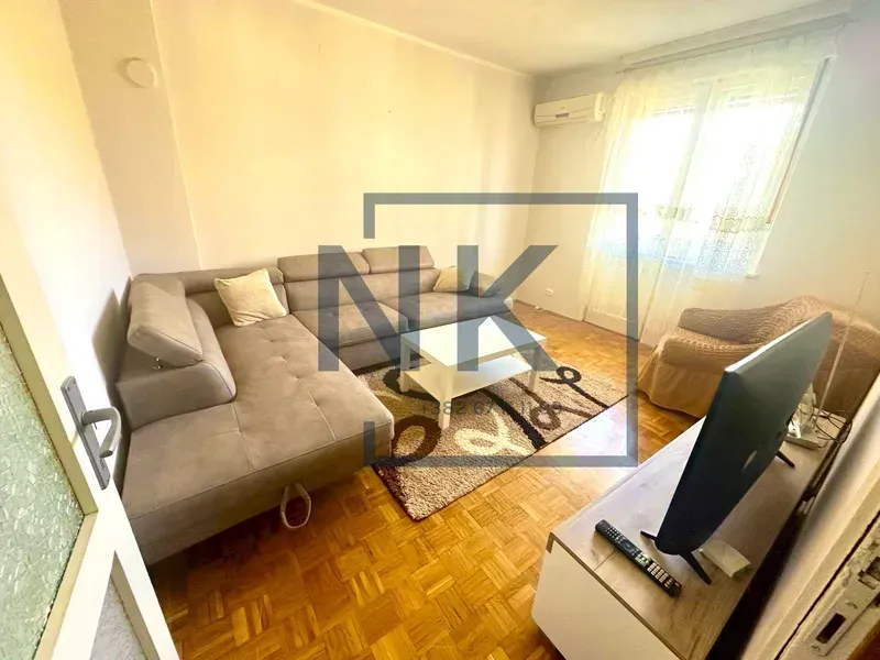 Living room with a sofa, TV, and parquet flooring.