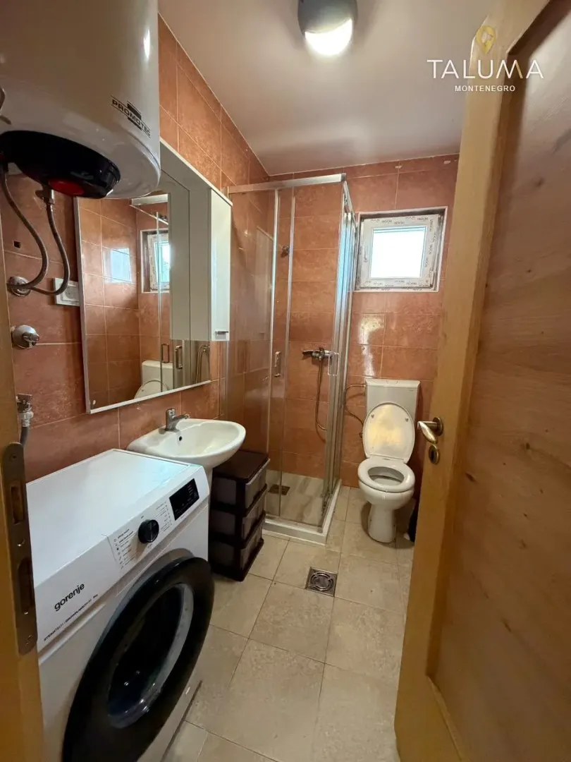 Bathroom equipped with a shower cabin, washbasin, toilet, and washing machine.