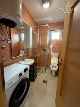 Bathroom equipped with a shower cabin, washbasin, toilet, and washing machine. - image 9