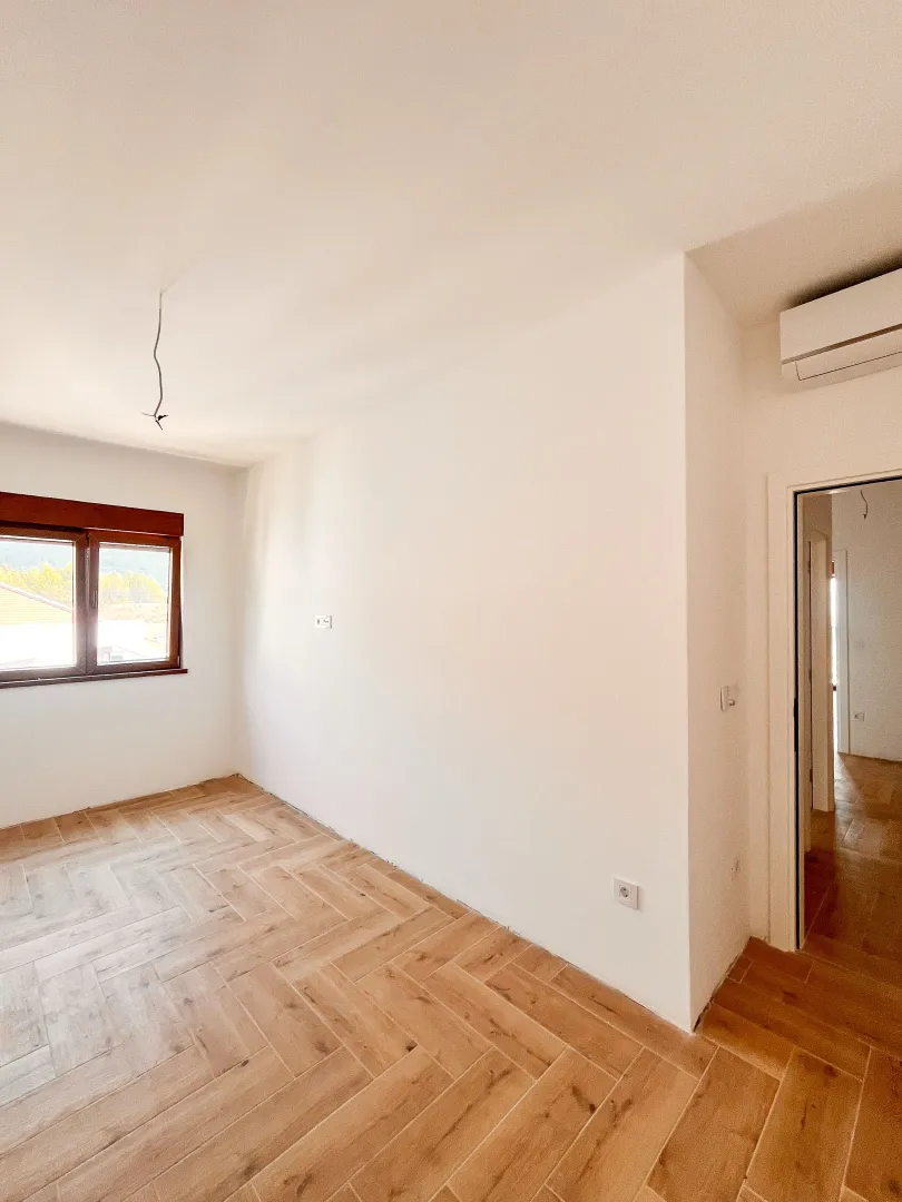 Prazna soba sa parketom i prozorom.