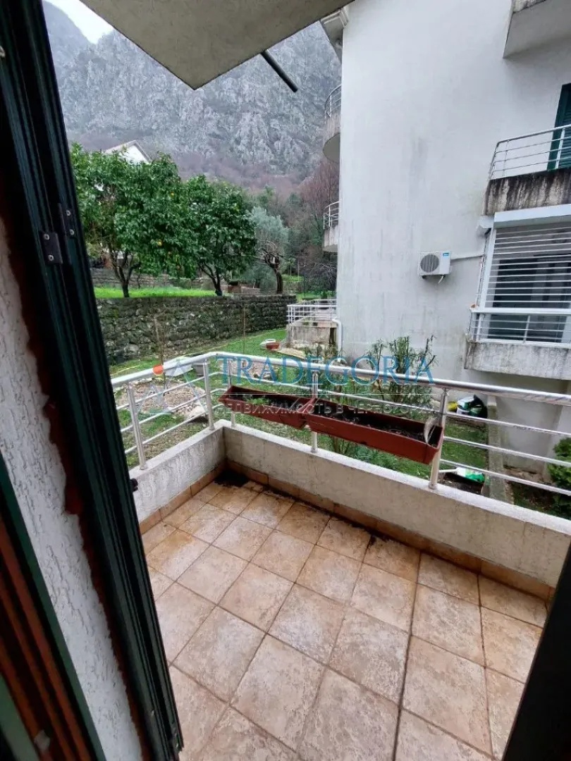 Manji popločani balkon sa metalnom ogradom i pogledom na dvorište i planinu.