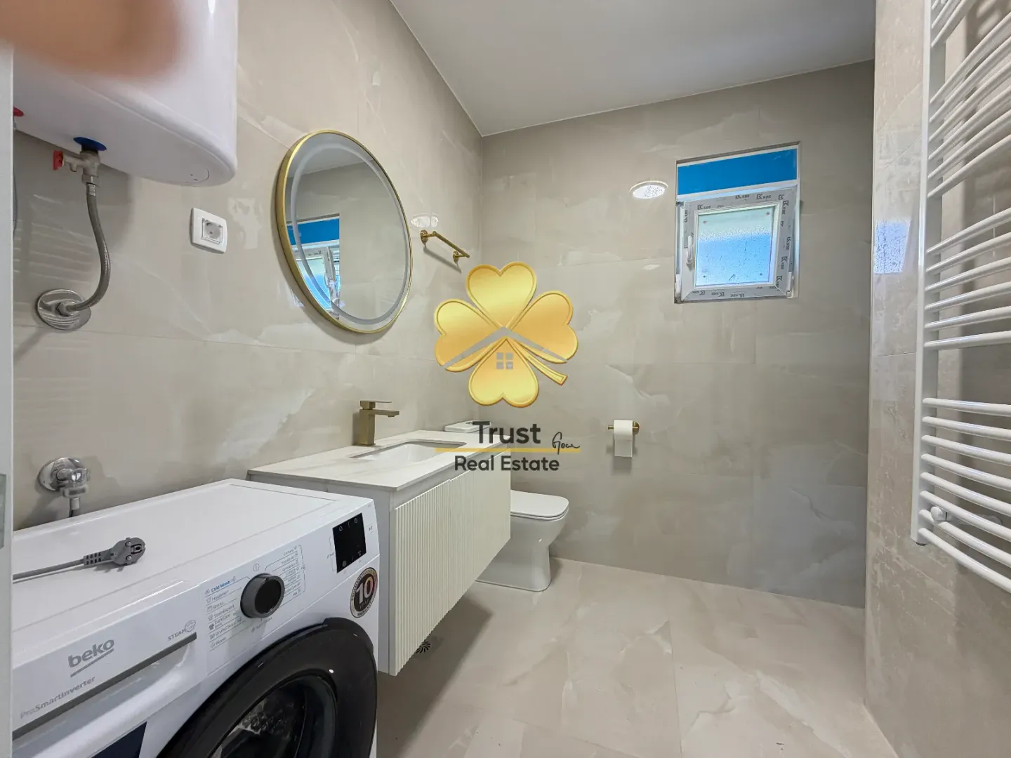 Modernly equipped bathroom with a washbasin, mirror, and washing machine.