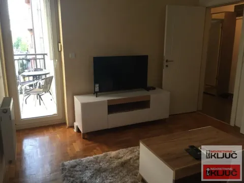Dnevna soba sa televizorom, komodom i izlazom na terasu. - image 2