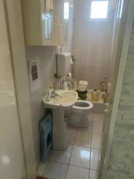 Small tiled bathroom equipped with a washbasin, toilet, and bathtub. - image 4