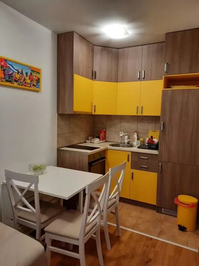 Small kitchen with yellow cabinets and a dining table with chairs.