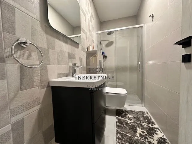 Modern bathroom with a washbasin, shower cabin and toilet.