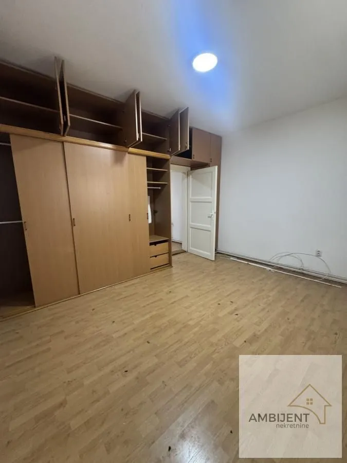 Spavaća soba sa ugradnim ormarom i drvenim podom.