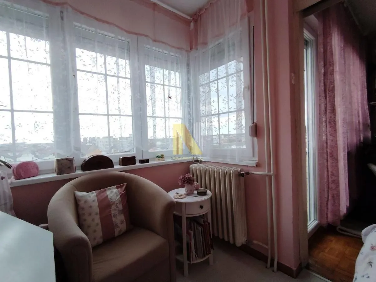 Manji kutak za sedenje sa foteljom pored prozora u roze sobi.