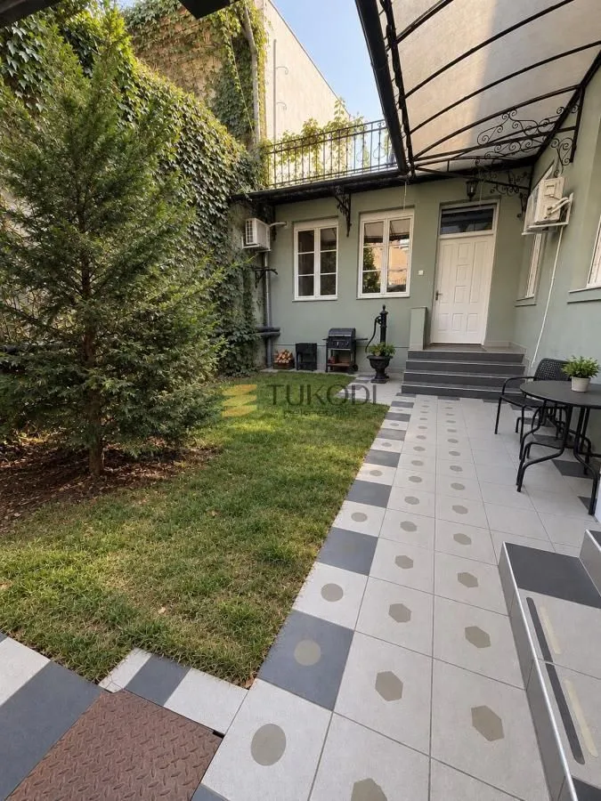 Landscaped courtyard with a lawn, paved area, and outdoor seating.