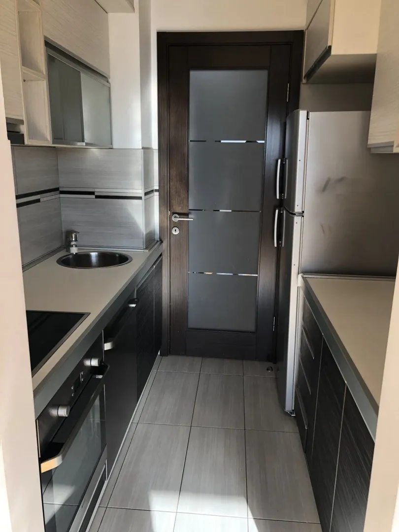 Narrow kitchen with modern cabinets and appliances.