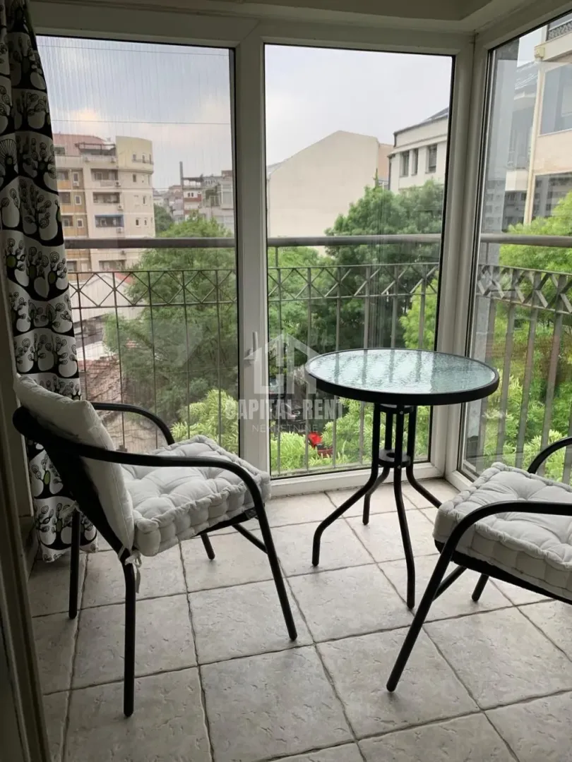 Enclosed balcony with a small table, chairs, and a view of the surroundings.