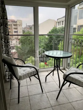Enclosed balcony with a small table, chairs, and a view of the surroundings. - image 13