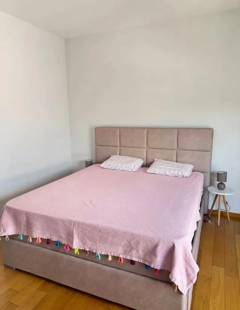 Spavaća soba sa bračnim krevetom i noćnim stočićem.